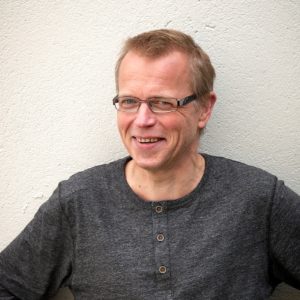 Bildet viser mann med brille og i grå genser, navnet hans er Per Kristian Alnes